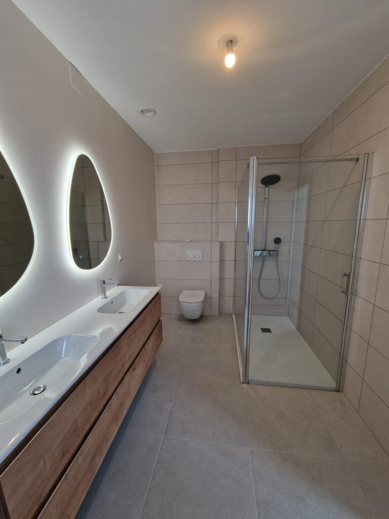 Aménagement salle de bain contemporaine avec douche vitrée, meuble double vasque et WC suspendu – travaux plomberie DK Concept